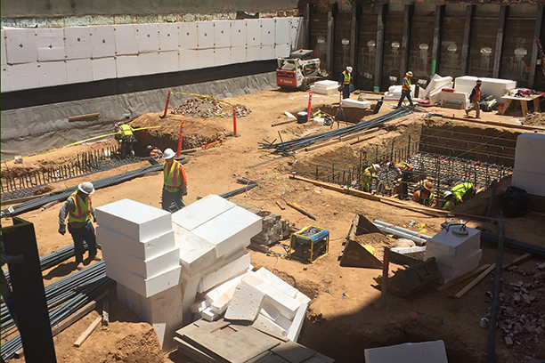 below grade commercial project with many workers in hard hats\