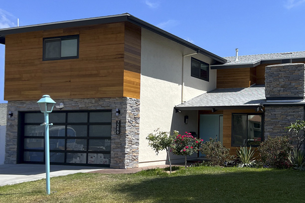 1970's updated track home with wood siding and modern steal glass garage door